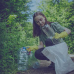 A woman outside putting plastic bottles into a bag.