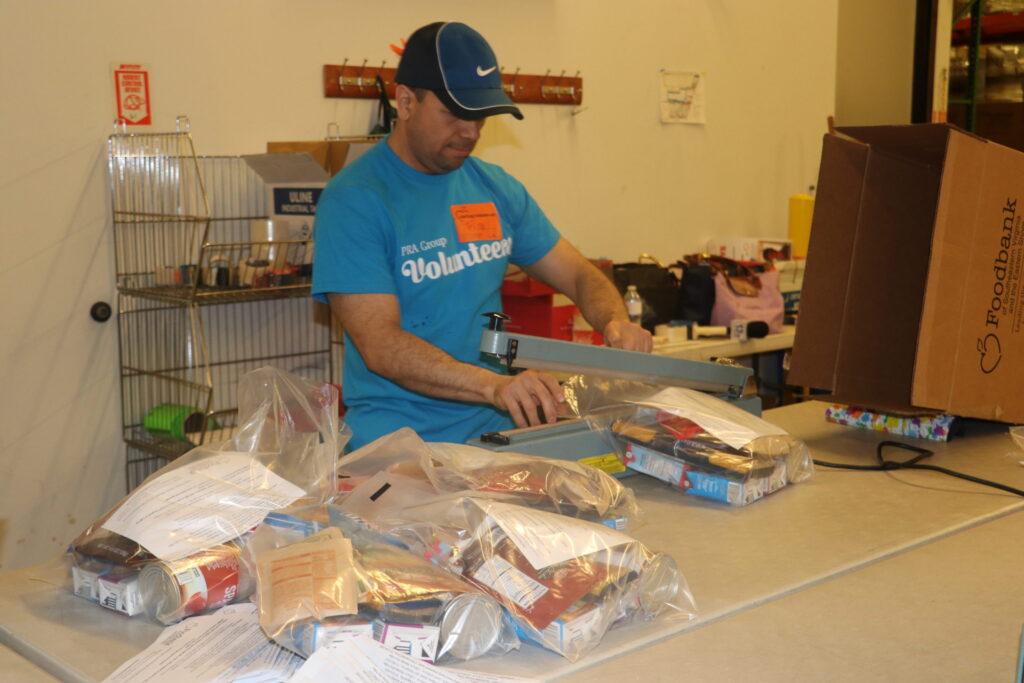 A PRA employee fills a bag with food while volunteering.