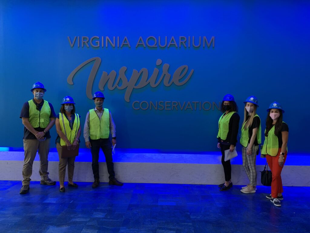 Aquarium employees gather in front of an "Inspire Conservation" sign.