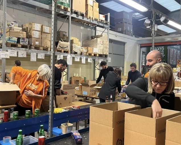 An action shot of a group of volunteers packing boxes in a food bank.