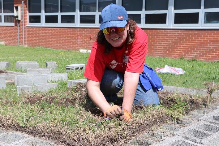 A woman smiling while working in a garden.