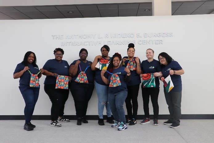 A group of eight volunteers holding Smile Bags that they have just sewn and packed.