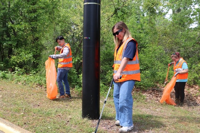 A volunteer smiling while cleaning up litter.