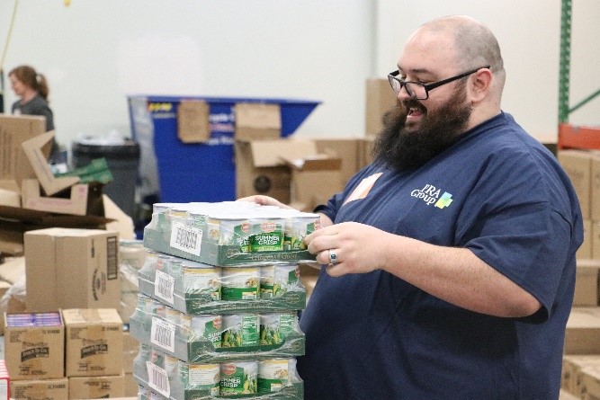 A man unloading a stack of canned green beans.